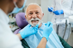 Senior patient smiling while dentist examines his teeth