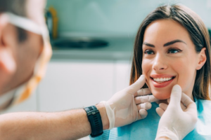 Woman smiling while dentist inspects her teeth