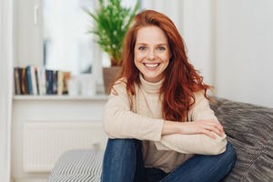 Woman in sweater sitting on couch and smiling