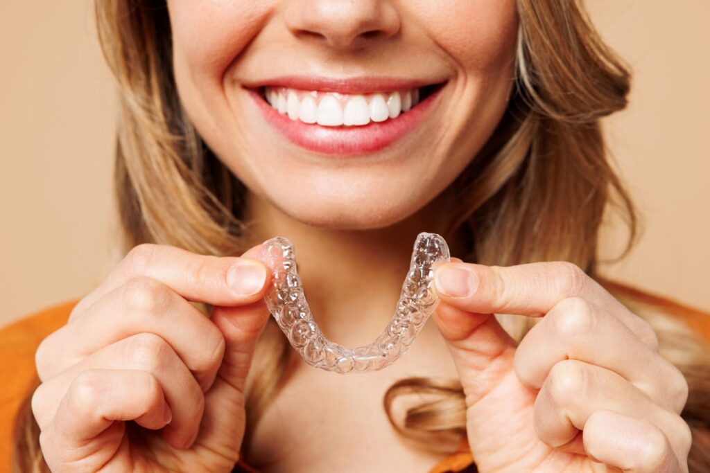 A woman holding an Invisalign aligner